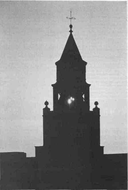 Morning sun shines through a silhouette of the clock tower atop Pulliam Hall